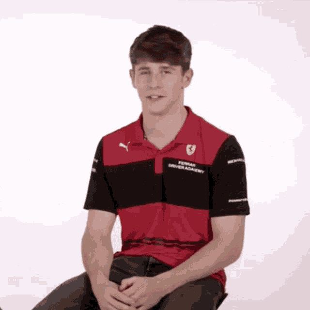 a man wearing a red and black ferrari driver academy shirt