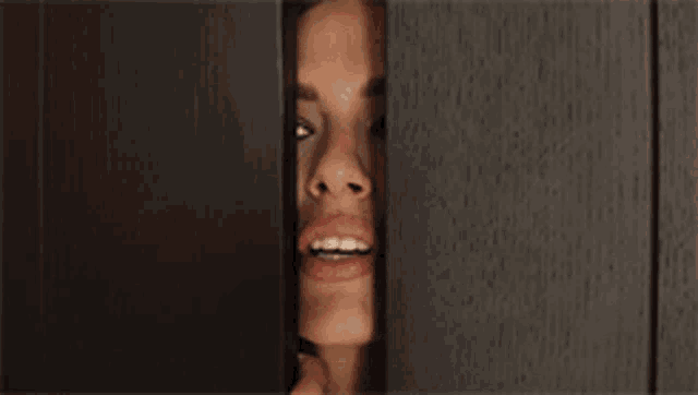 a close up of a woman 's face peeking through a door .
