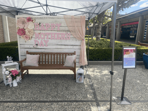 a happy mother 's day sign hangs over a bench