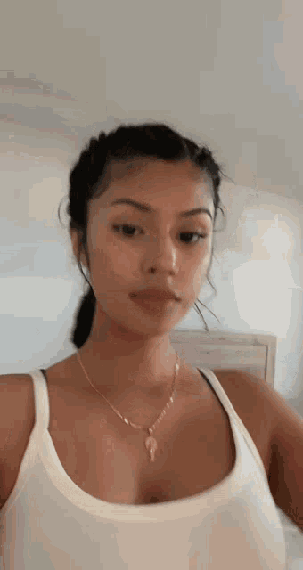 the woman is wearing a white tank top and a necklace .