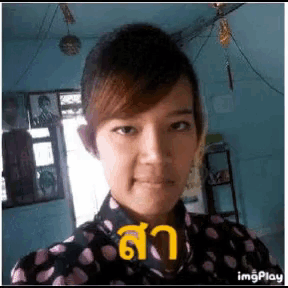 a woman in a polka dot shirt is taking a selfie in a room with a blue wall .