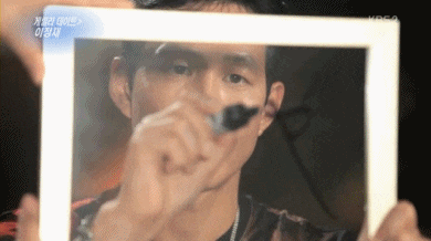 a man in a black shirt is holding a white frame with a picture of him on it