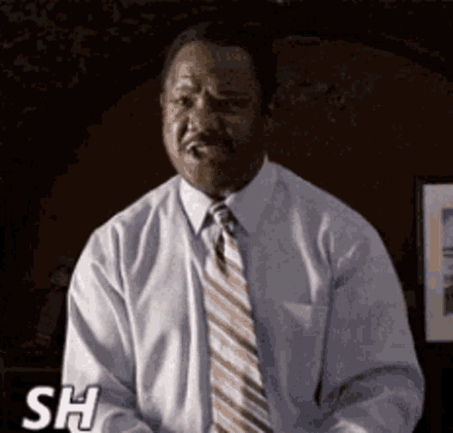 a man in a white shirt and tie is making a funny face with the letters sh above him