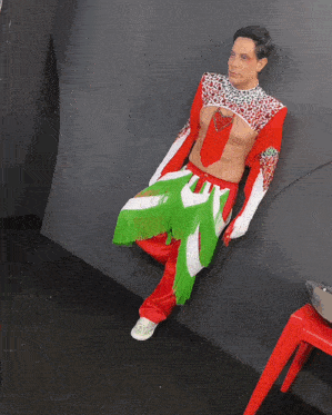 a man in a red white and green outfit is sitting on a chair