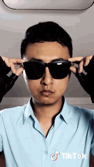 a man wearing sunglasses and a blue shirt has tiktok written on the bottom right