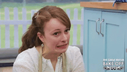 a woman is making a funny face in front of a blue cabinet in a kitchen .