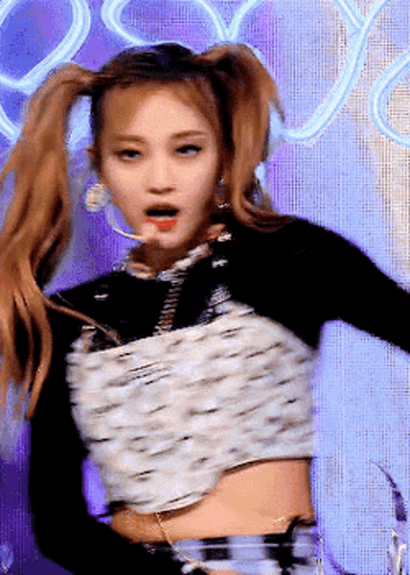 a woman with pigtails is wearing a crop top and a black sweater .