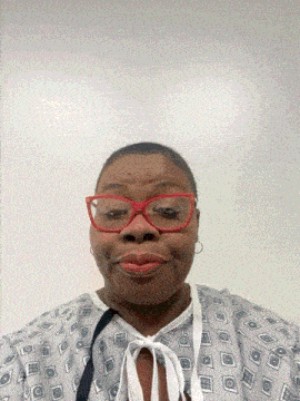 a woman wearing glasses and a hospital gown smiles