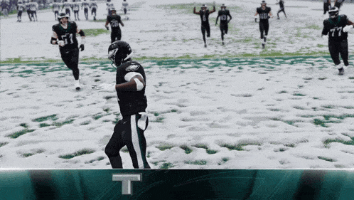 a football player with the number 11 on his jersey runs on a snowy field