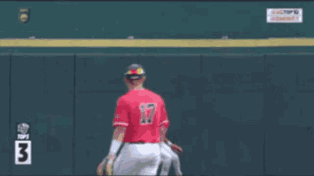a baseball player stands in front of a wall with the number 3
