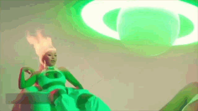 a woman in a green dress is sitting in front of a green circle .