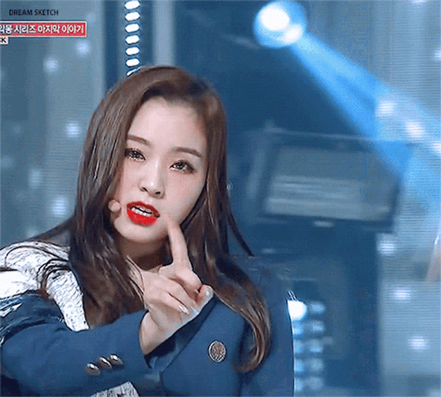 a girl in a blue jacket and red lipstick is giving the middle finger