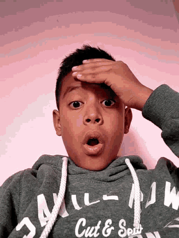 a young boy wearing a grey hoodie that says " cute & sexy "