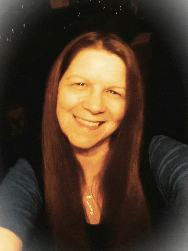 a woman with long brown hair and a blue shirt smiles
