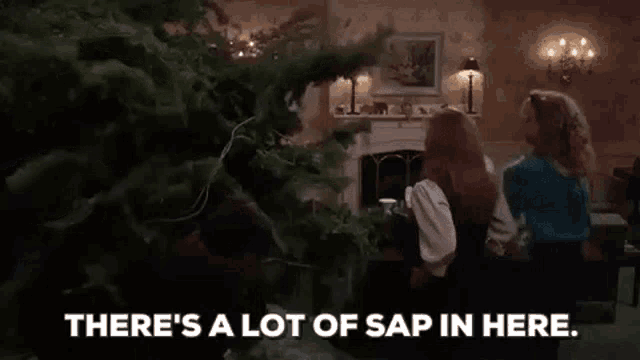 a group of people are sitting in a living room looking at a christmas tree .