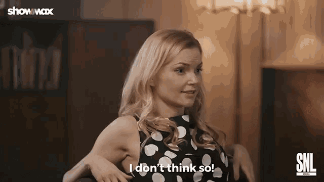a woman in a polka dot dress is sitting on a couch and saying `` i don t think so '' .