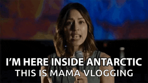 a woman is standing in front of a microphone and says `` i 'm here inside antarctica this is mama vlogging ''