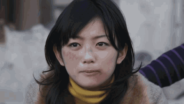 a woman with a bruise on her face is wearing a yellow sweater