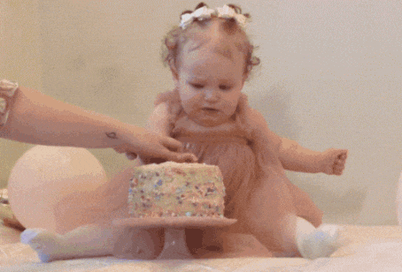 a little girl is crying while playing with a cake