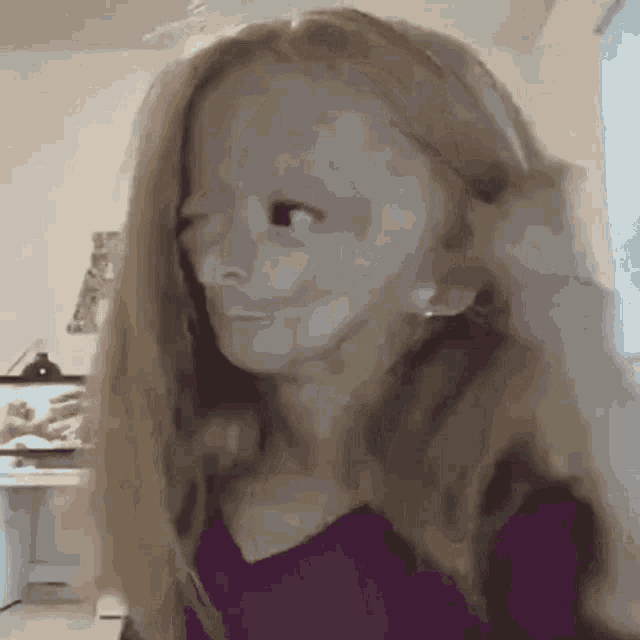a little girl with long blonde hair is looking at the camera