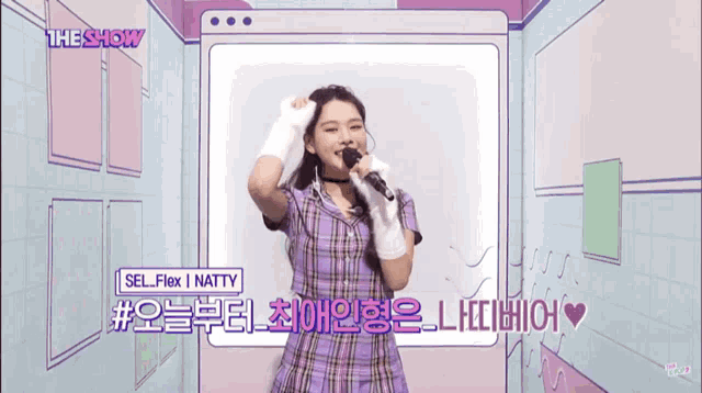 a girl in a purple plaid dress sings into a microphone with the show written on the bottom