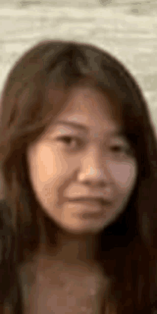 a close up of a woman 's face with long hair and a blurred background .