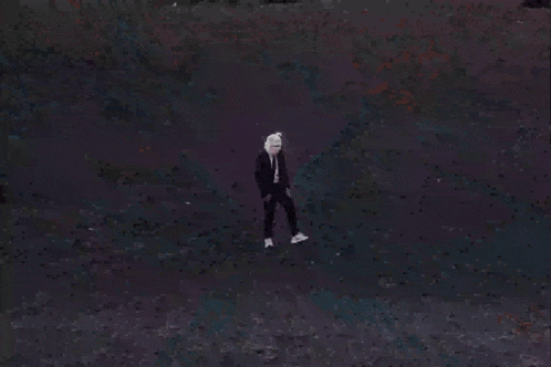a man in a suit and tie is standing on top of a hill wearing a pink pig mask .