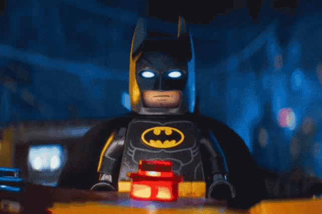 a close up of a lego batman holding a red light