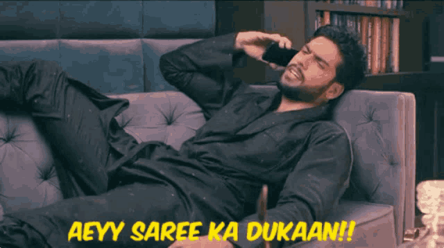 a man laying on a couch talking on a cell phone with the words aeyy saree ka dukaan