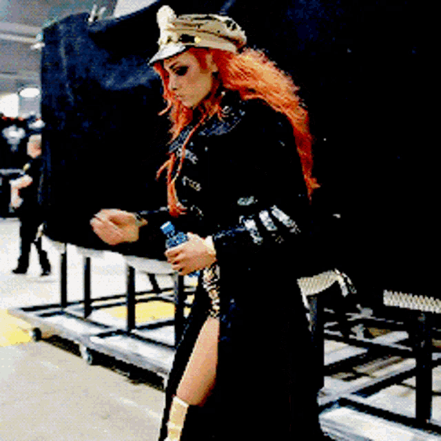 a woman with red hair is wearing a hat and holding a bottle