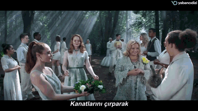a group of people are standing in a forest and the words kanatlarini cirparak are on the screen