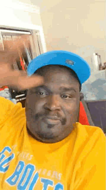 a man wearing a blue hat and a yellow shirt that says ' denver broncos ' on it