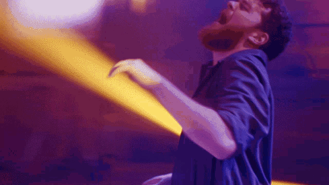 a man in a blue shirt is dancing in a club