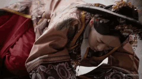 a woman in a traditional chinese dress is kneeling down .