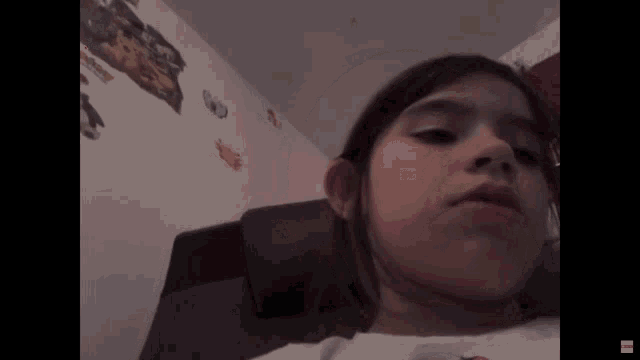 a little girl is sitting in a chair with a sticker on the wall that says ' avengers '