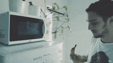 a man holding a banana in front of a microwave that says ok