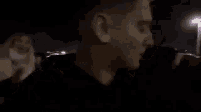 a blurry picture of a man standing in front of a crowd of people at night .