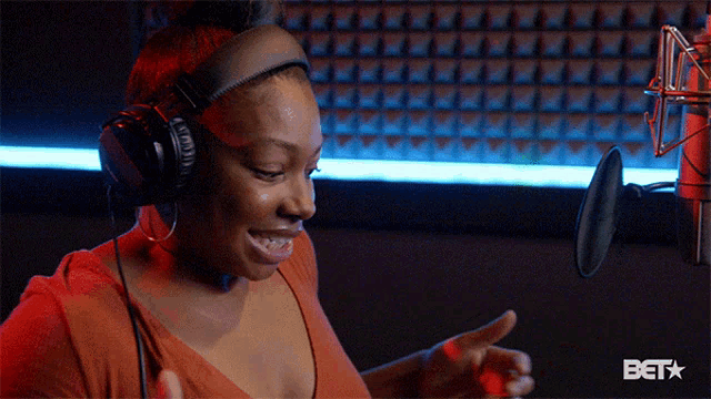 a woman wearing headphones is smiling in front of a microphone that says bet on it