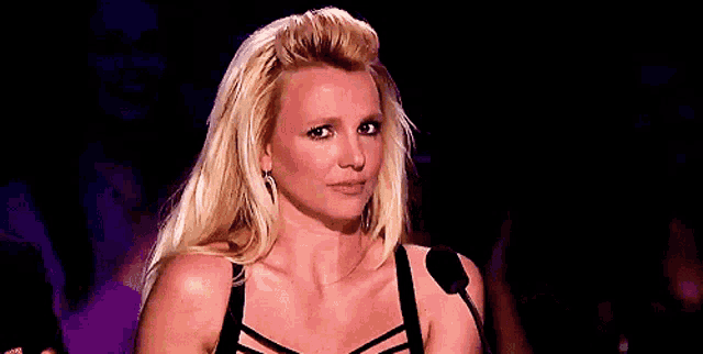 a woman with blonde hair is making a funny face while standing in front of a microphone