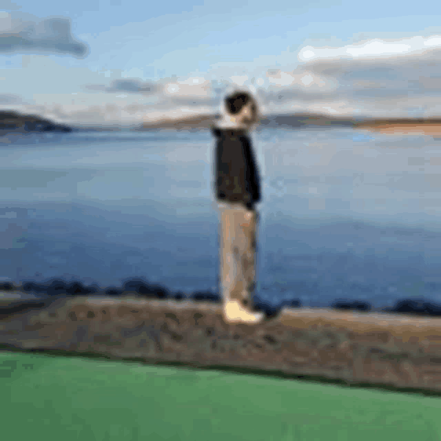 a person is standing on the edge of a body of water looking at the water .