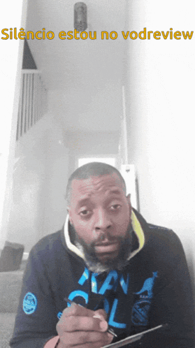 a man with a beard is writing on a piece of paper with the words silencio estou no vodview above him