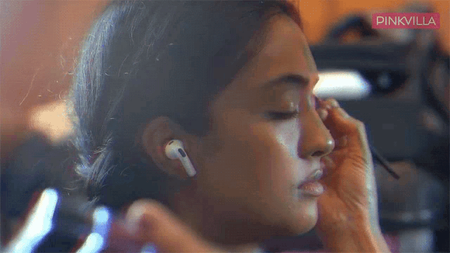 a close up of a woman wearing ear buds with pinkvilla written on the bottom