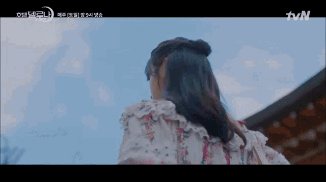 a woman in a floral dress is standing in front of a building with tvn written on the bottom