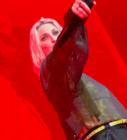 a woman is singing into a microphone in front of a red background .
