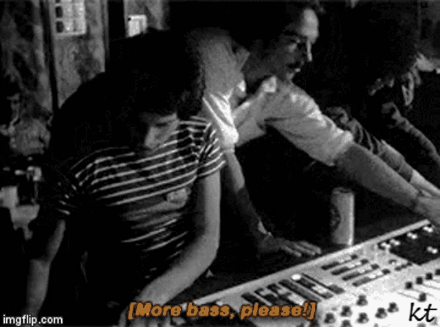 a black and white photo of two men sitting at a table playing a keyboard .