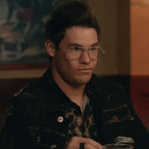 a man wearing glasses and a black jacket has a button on his jacket that says ' i love you ' on it