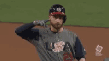 a baseball player wearing a usa jersey and a helmet is standing on a baseball field .