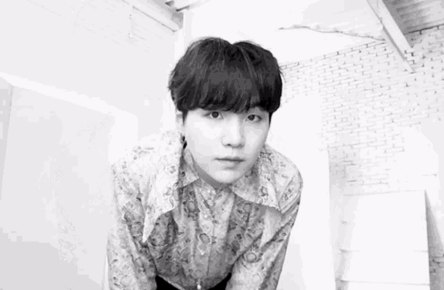 a black and white photo of a young man wearing a floral shirt .