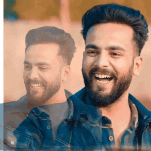a man with a beard is smiling in front of a wall