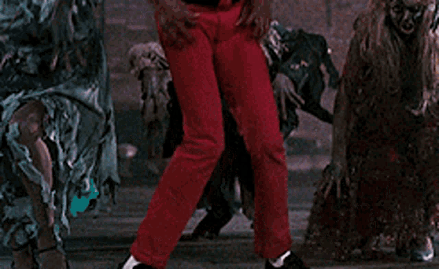 a man in a red costume says aaow in front of a crowd of zombies